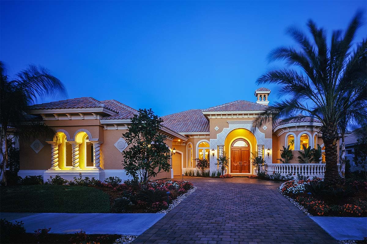 House plan exterior: One-story Mediterranean style with arched entry, decorative columns, tile roof, and side-facing garage.