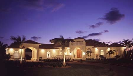 House plan exterior with arched entryway, porte-cochère, and second-story balcony with balustrade.