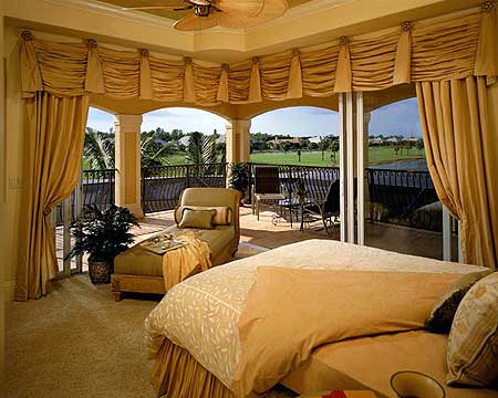 Bedroom with covered balcony access featuring chaise lounge, golf course, and water views.