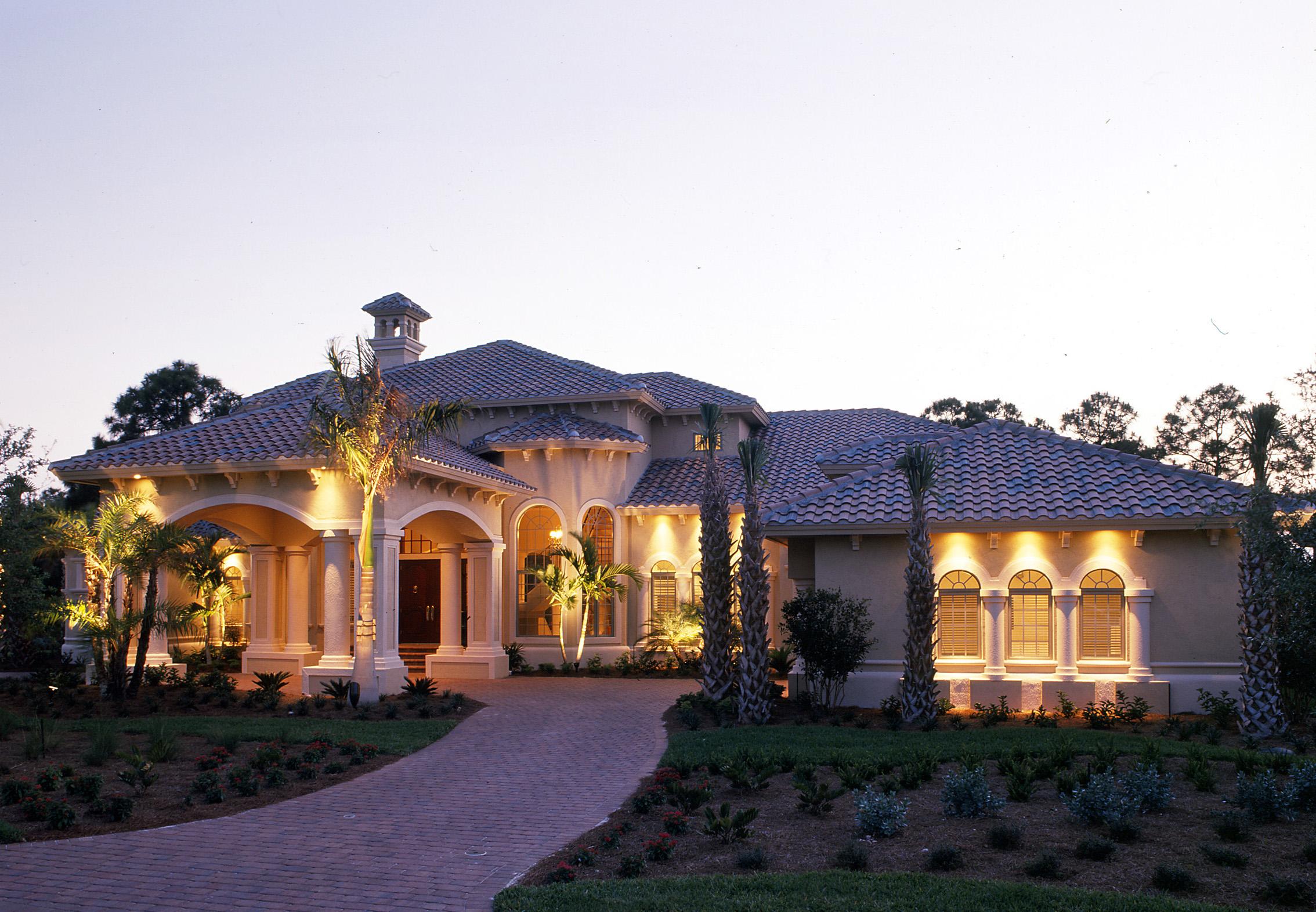 House plan exterior of one-story Mediterranean style home with arched entryway, covered porch, tile roof, and decorative chimney.