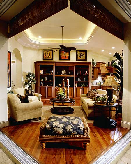 Interior view of a great room with built-in bookshelves, sofas, coffee table, and a ceiling fan.