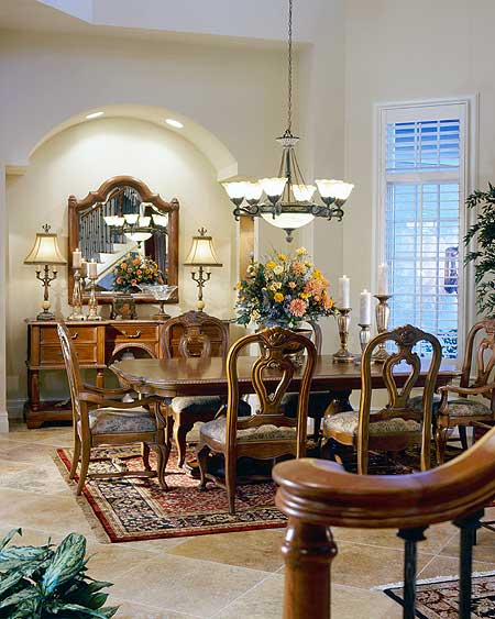 Dining room with ornate wooden chairs, a dark wood table, buffet, and mirrored wall.