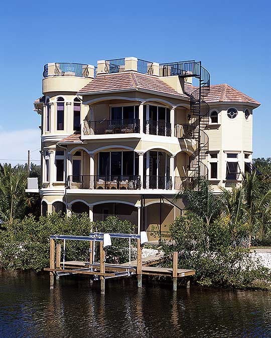 House plan exterior: multi-story house with rounded towers, balconies, tile roof, and spiral staircase to rooftop deck.