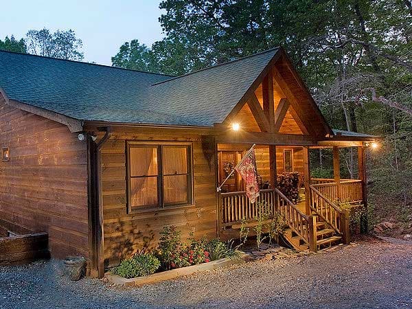 House plan exterior: log cabin style, one story, with covered porch, exposed rafter tails, and wood siding.
