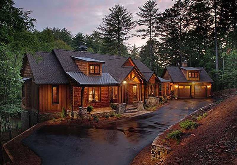 House plan exterior: Log home with stone accents, gabled roofs, dormers, covered porch, and attached two-car garage.