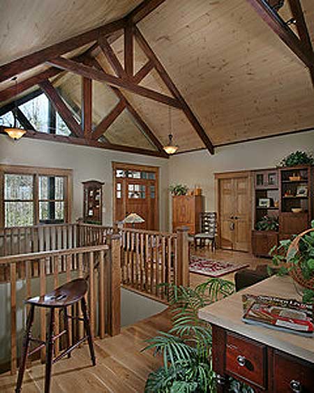 Interior view of house with vaulted wood ceiling, exposed beams, wood railings, and glass-paneled double doors.