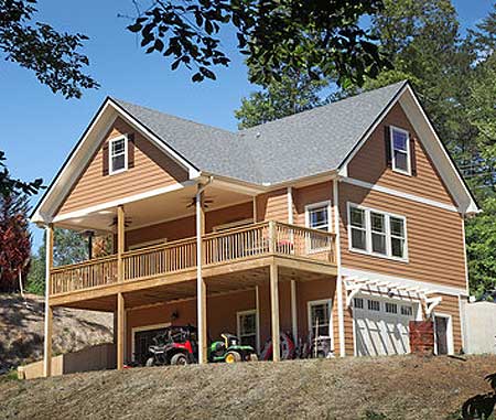 House plan exterior: Two-story home with a wraparound deck, gables, dormer window, and a side-entry garage.