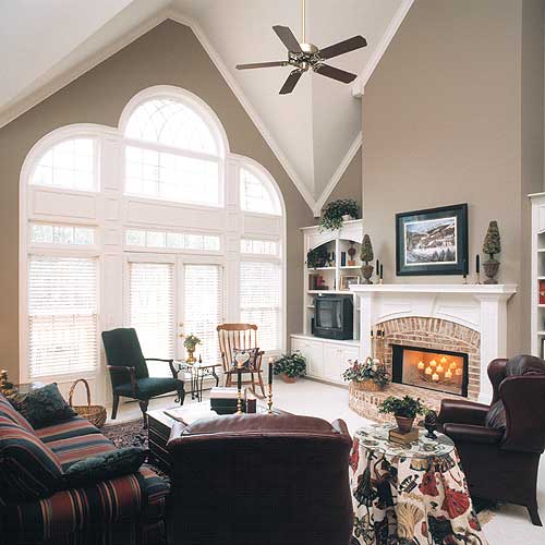 Great room with vaulted ceiling, fireplace, built-in shelving, and arched window wall.