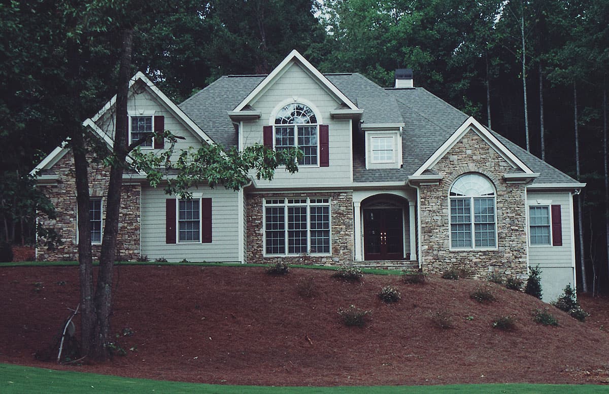 House plan exterior, two stories, stone accents, arched windows, covered entryway, and multiple gables.