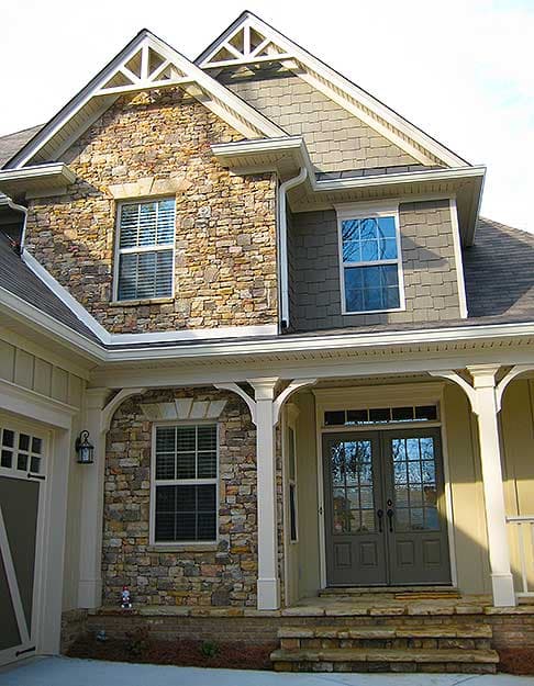 House plan exterior: two-story home with stone accents, gabled dormers, double front doors, and a covered porch.