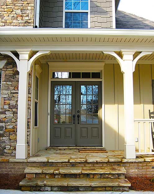 House plan exterior with stone and siding, double-door entry, covered porch with columns, and multi-level stone steps.