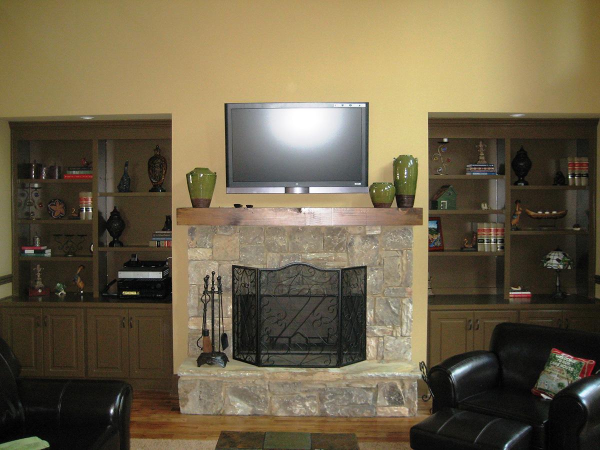 Living room fireplace with stone surround and hearth, flanked by built-in shelving units.