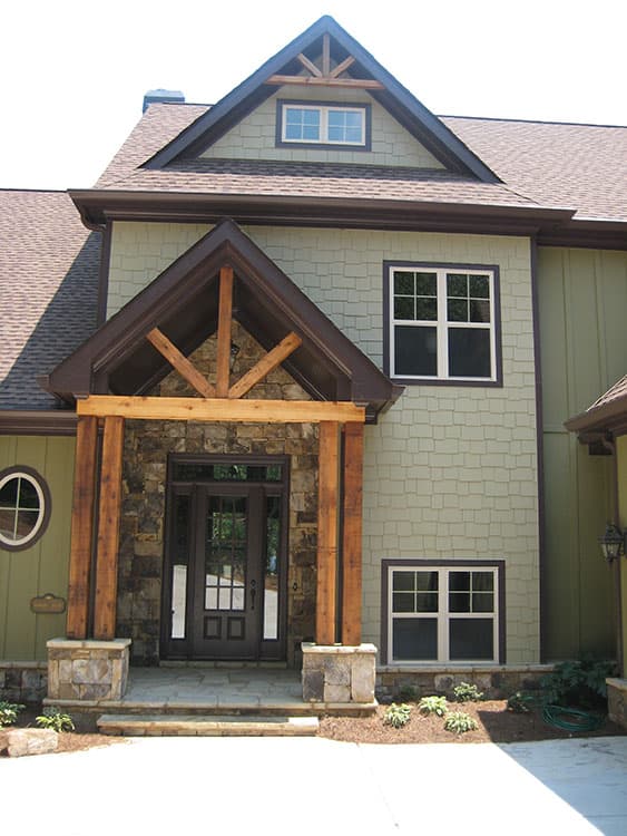 House plan exterior: Craftsman style with stone entry, timber posts, gabled dormer, and square windows.