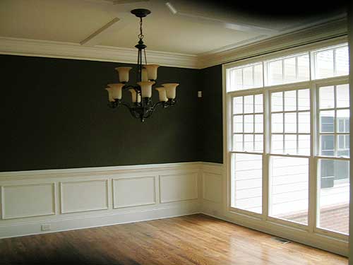 Interior view of dining room with coffered ceiling, chandelier, wainscoting, and large multi-pane windows.