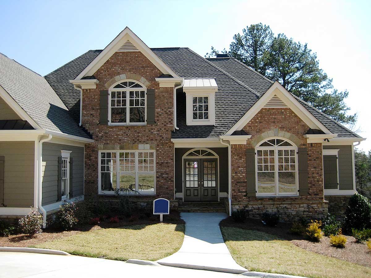 House plan exterior: Two-story brick home with gables, arched windows, dormer, and covered entry.
