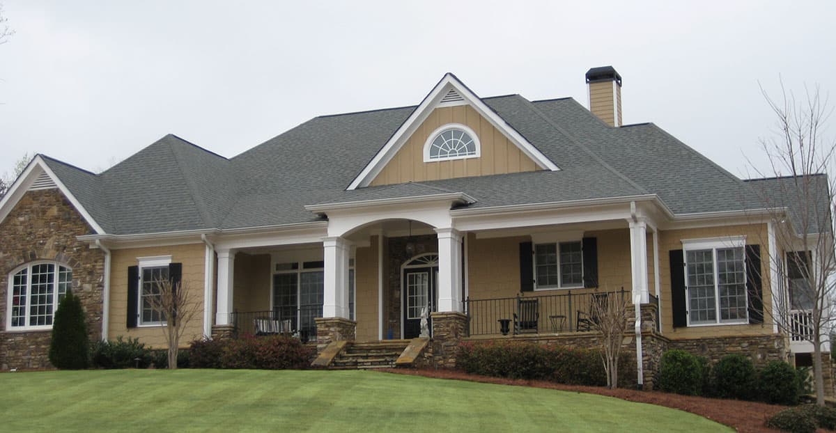 House plan exterior: One-story home with a covered entry porch, stone accents, multiple gables, and a prominent dormer.