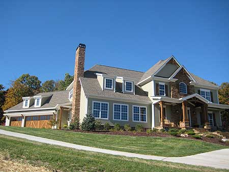 House plan exterior: Two-story home with brick chimney, dormers, covered entry, and a side-facing three-car garage.