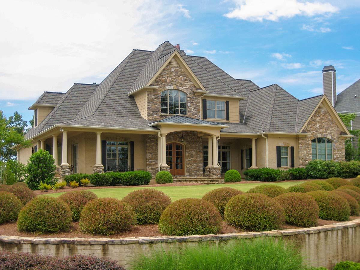 House plan exterior, two-story home with stone accents, wraparound porch, multiple gables, and dormers.