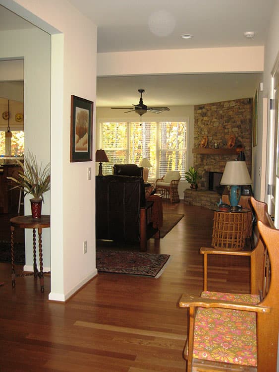 Interior view of an open-layout living space with stone fireplace, large windows, and wood flooring.