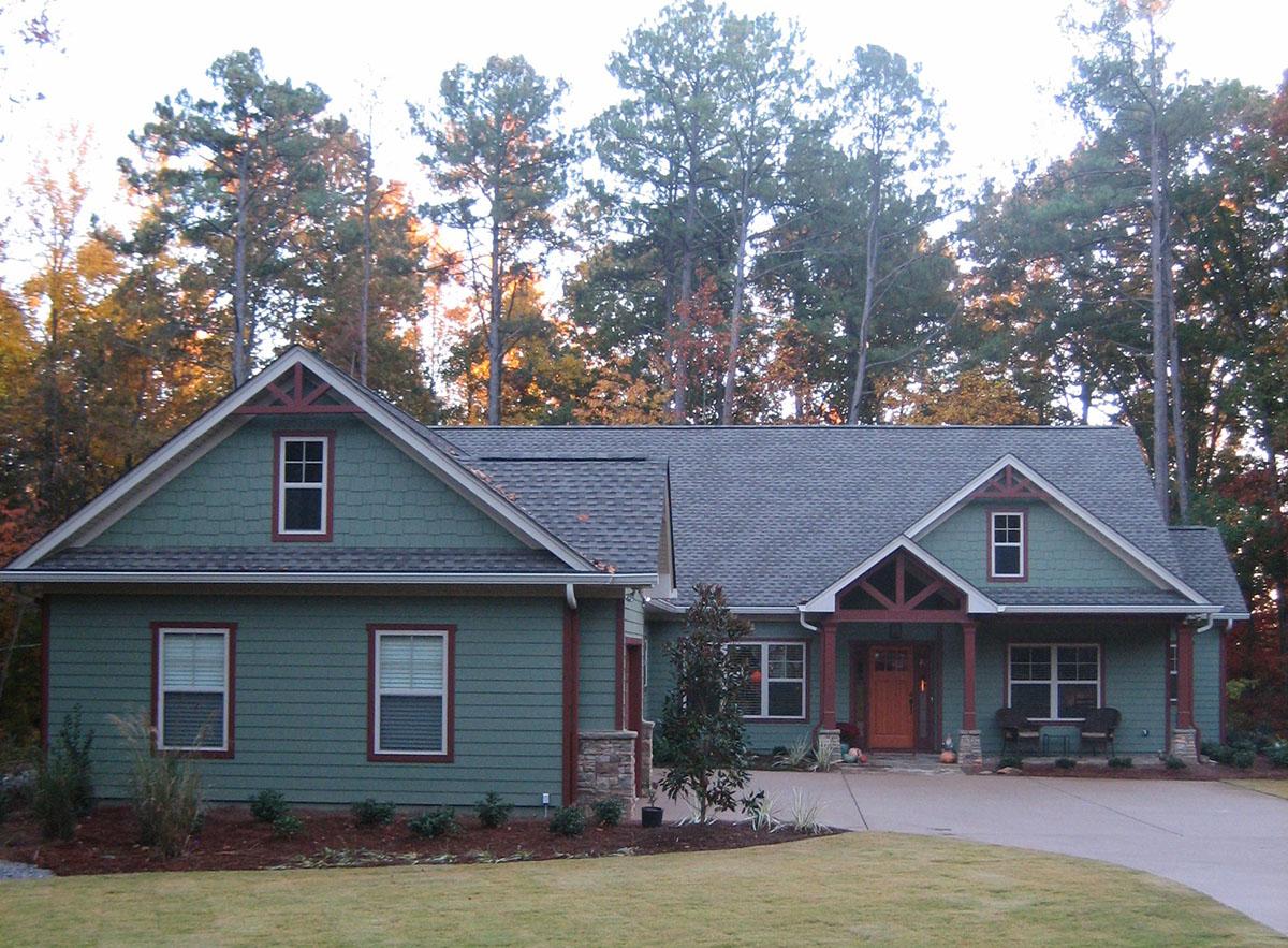 Craftsman style house plan exterior with green siding, prominent gables, covered entry porch, and stone accents.