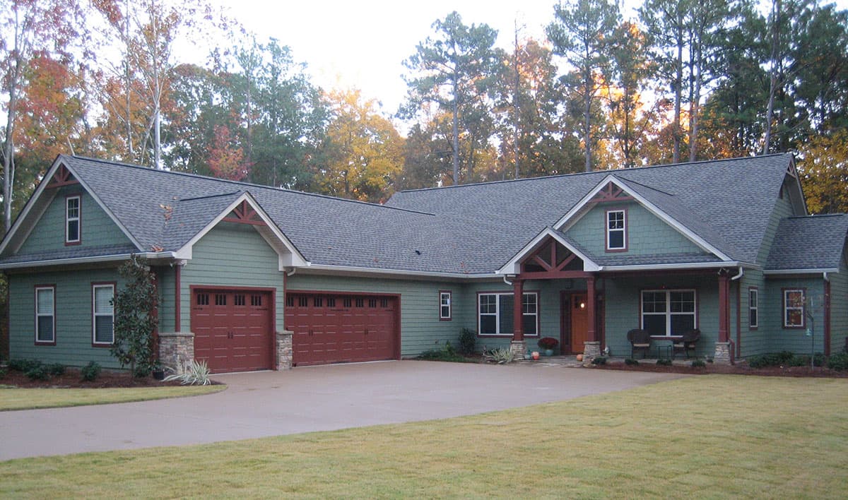 House plan exterior: Ranch style, one story with a covered front porch, three-car garage, and decorative gables.