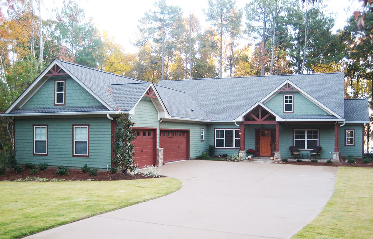 House plan exterior featuring a green, single-story Modern Farmhouse style with a gabled roof, wide porch, and a three-car garage.
