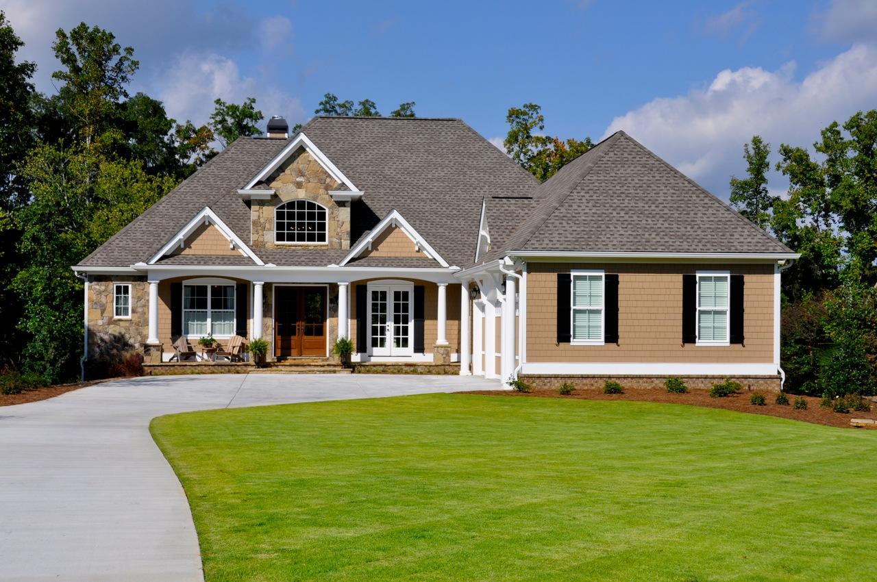 House plan exterior: One-story home with stone accents, gabled dormer, covered front porch with columns, and arched window.