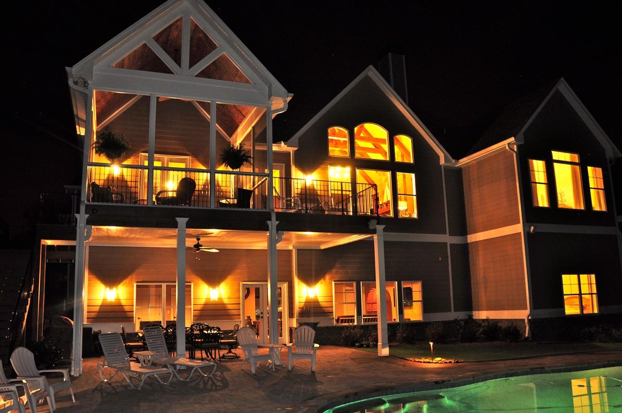 House plan exterior showing a multi-story home with a screened porch, gables, and arched upper windows.