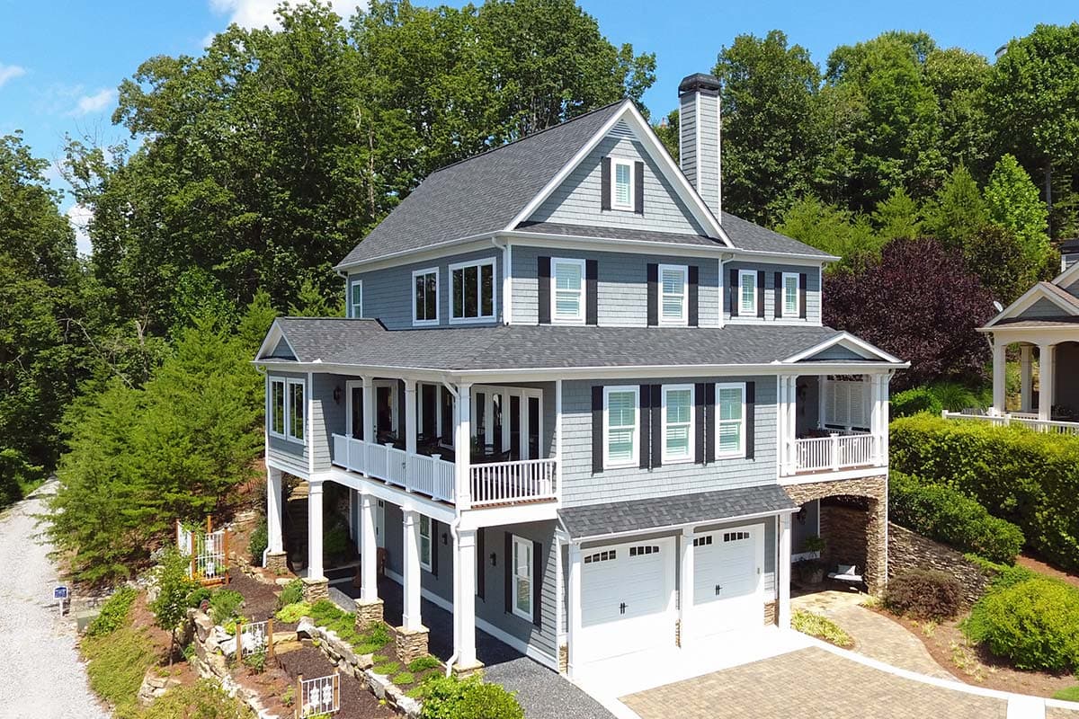 House plan exterior. Two-story shingle-style home with multiple gables, a covered porch, and a garage. The home has a symmetrical facade.