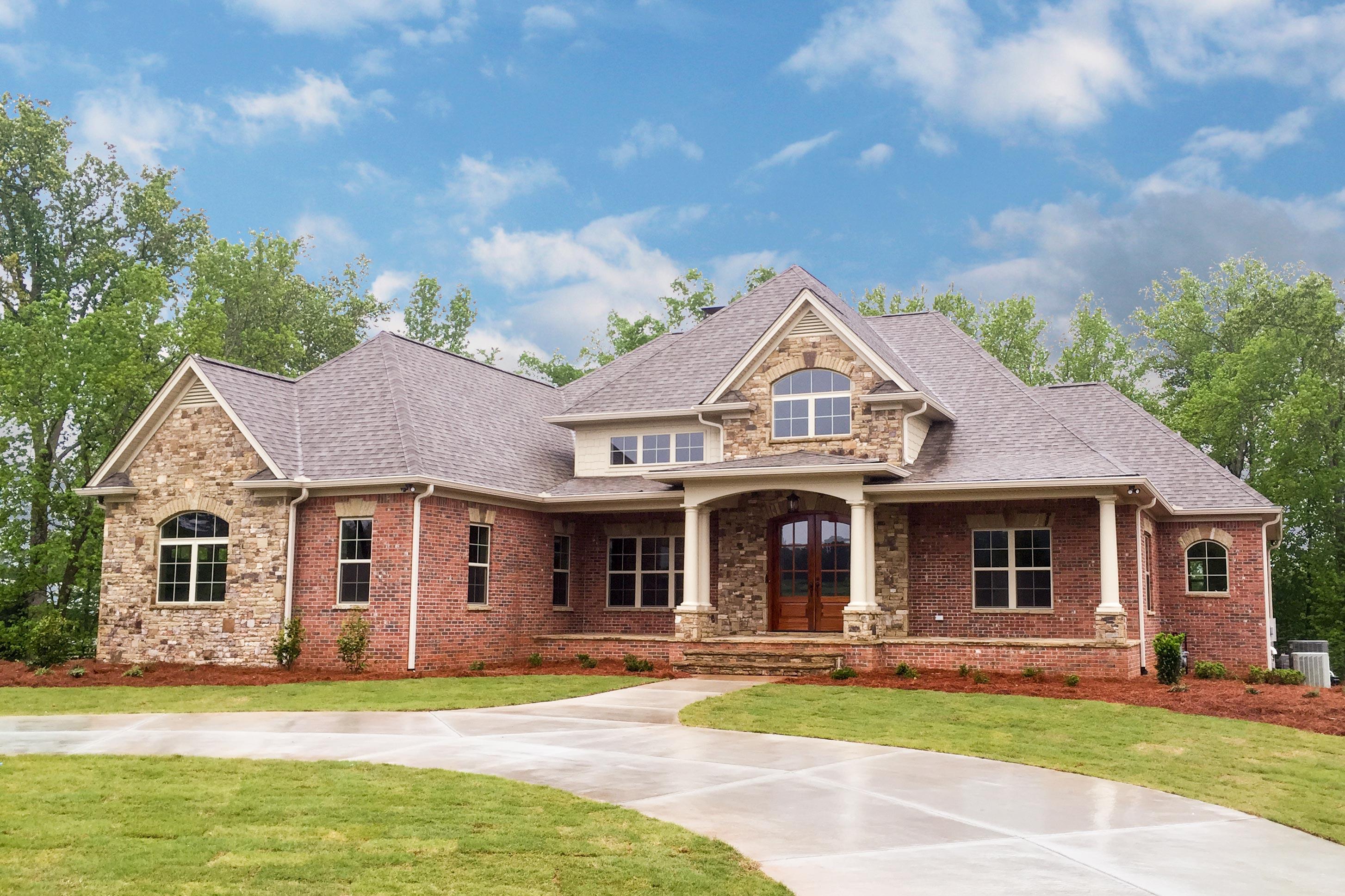House plan exterior. Two-story brick and stone facade. Features include a front porch, gables, and multiple rooflines.