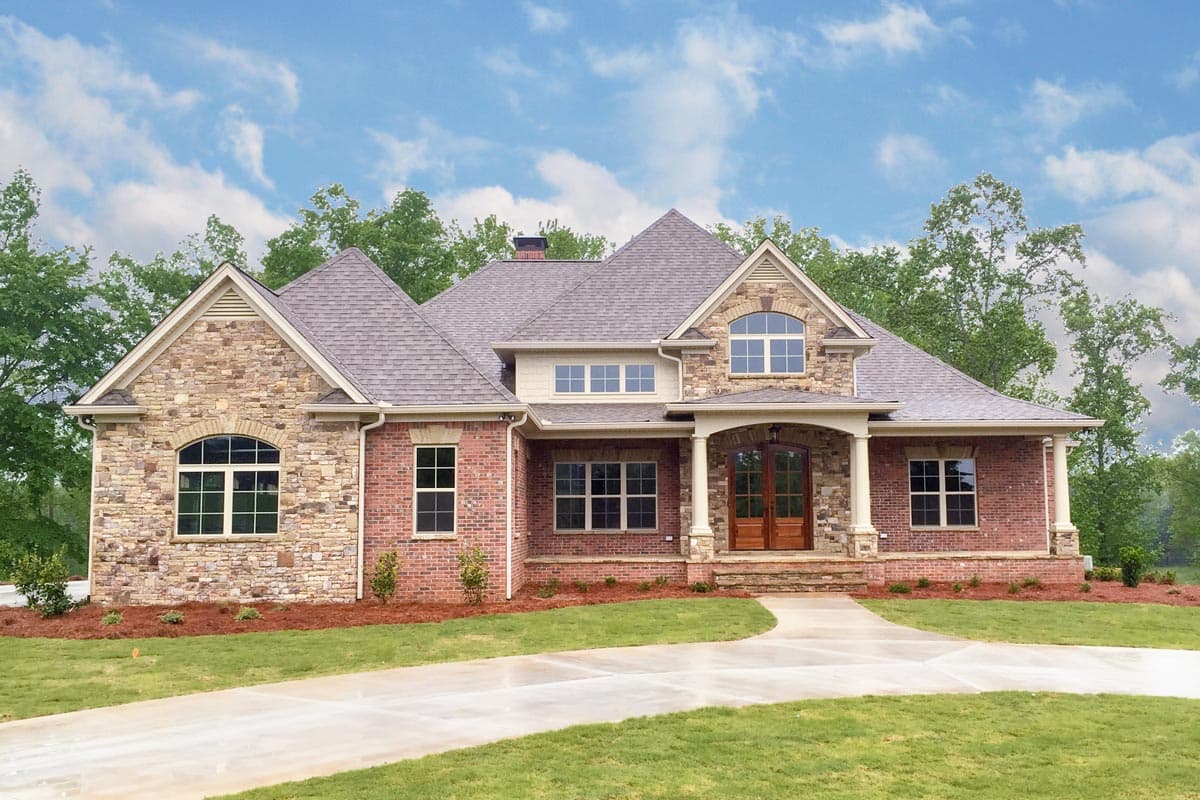 House plan exterior featuring brick and stone facade, two stories, gabled roof, arched windows, and covered entry with columns.