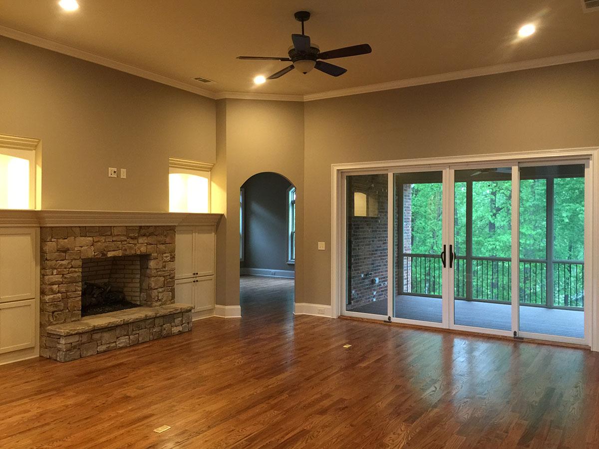 Living room with stone fireplace, built-in cabinetry, and sliding glass doors leading to a screened porch.