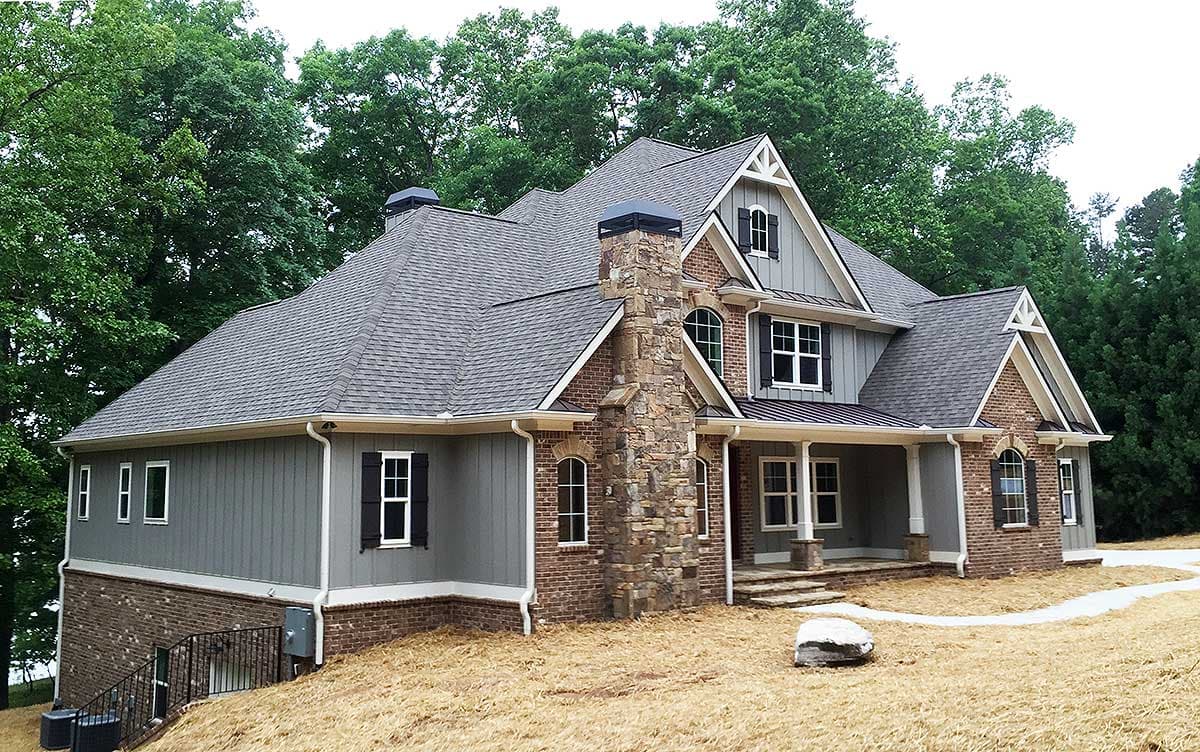 House plan exterior shows a two-story home with gables, a prominent stone chimney, and a covered porch.