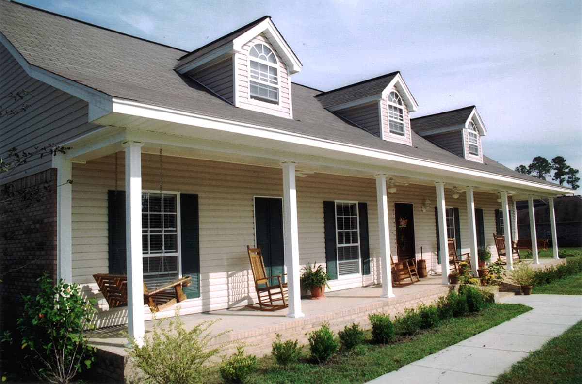 House plan exterior: Two-story home with a wrap-around porch, dormer windows, and vinyl siding.