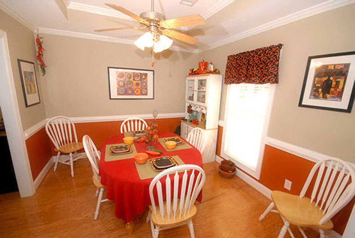Dining room with table set for four, white spindle-back chairs, ceiling fan, and wall art.