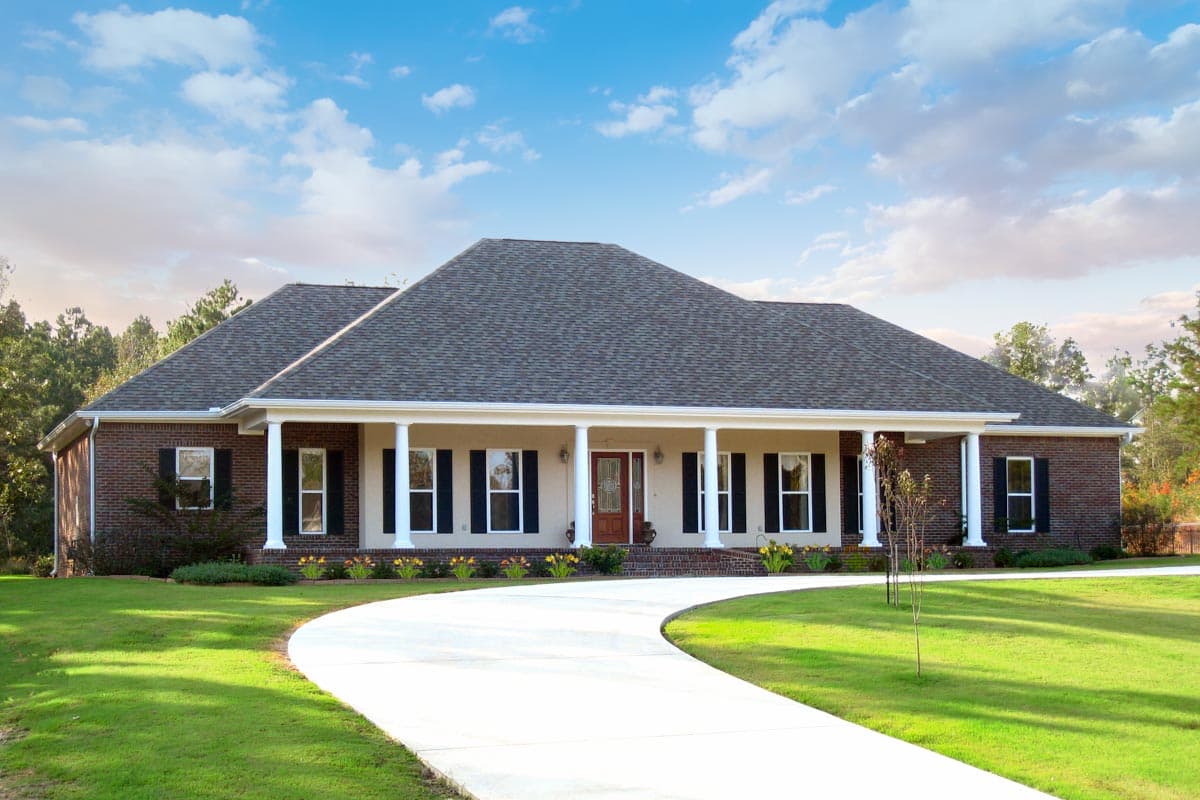 One-story house plan exterior with brick facade, wide covered porch supported by columns, central entry, and numerous windows.