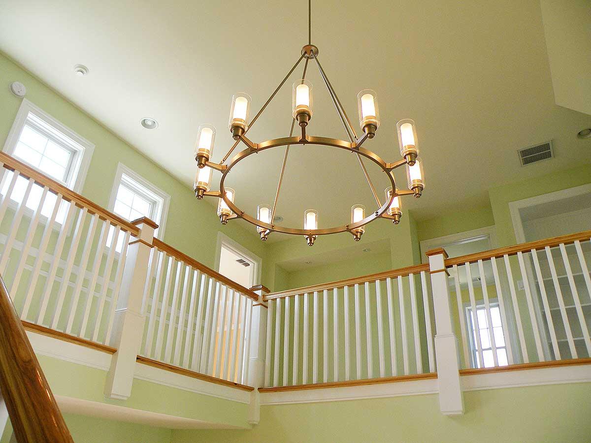 Interior view of a home showing a staircase railing and a large circular chandelier hanging from the ceiling.