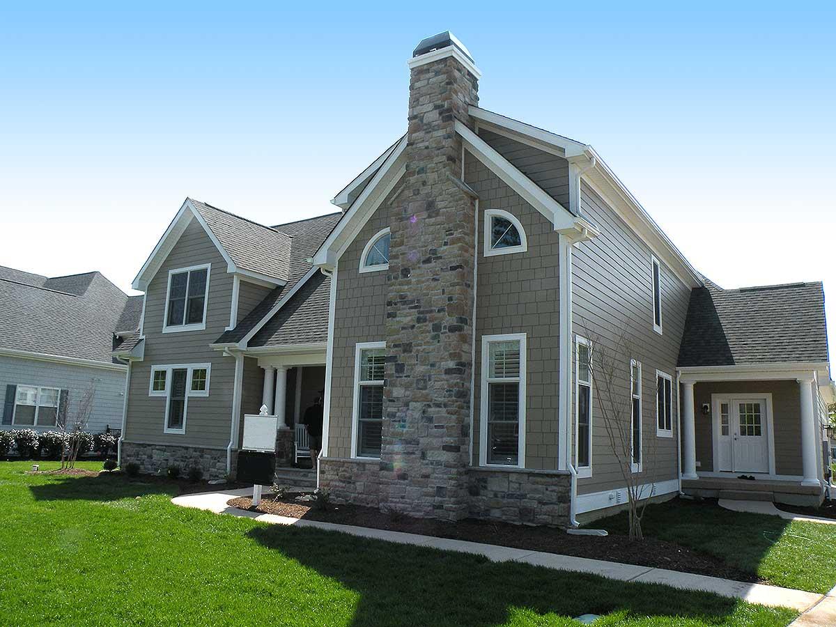 House plan exterior with stone chimney, gables, multiple dormers, and covered entry porch.
