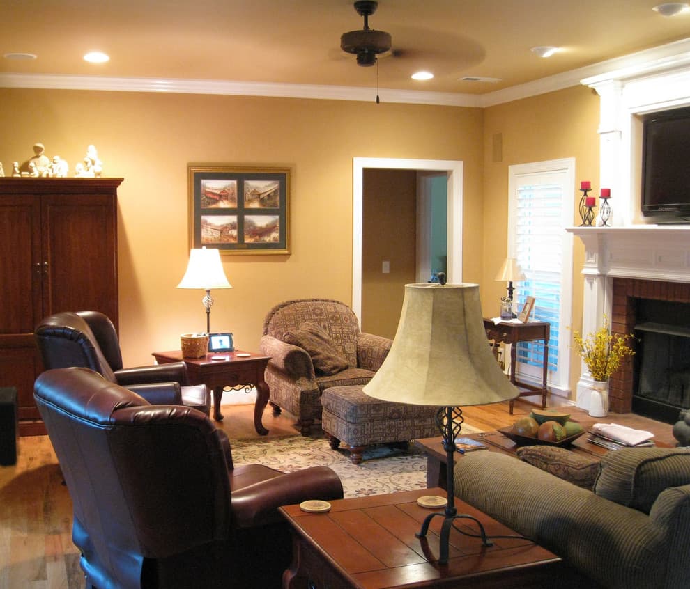 Living room with fireplace, large sectional sofa, patterned armchair, leather chairs, and a wooden cabinet.