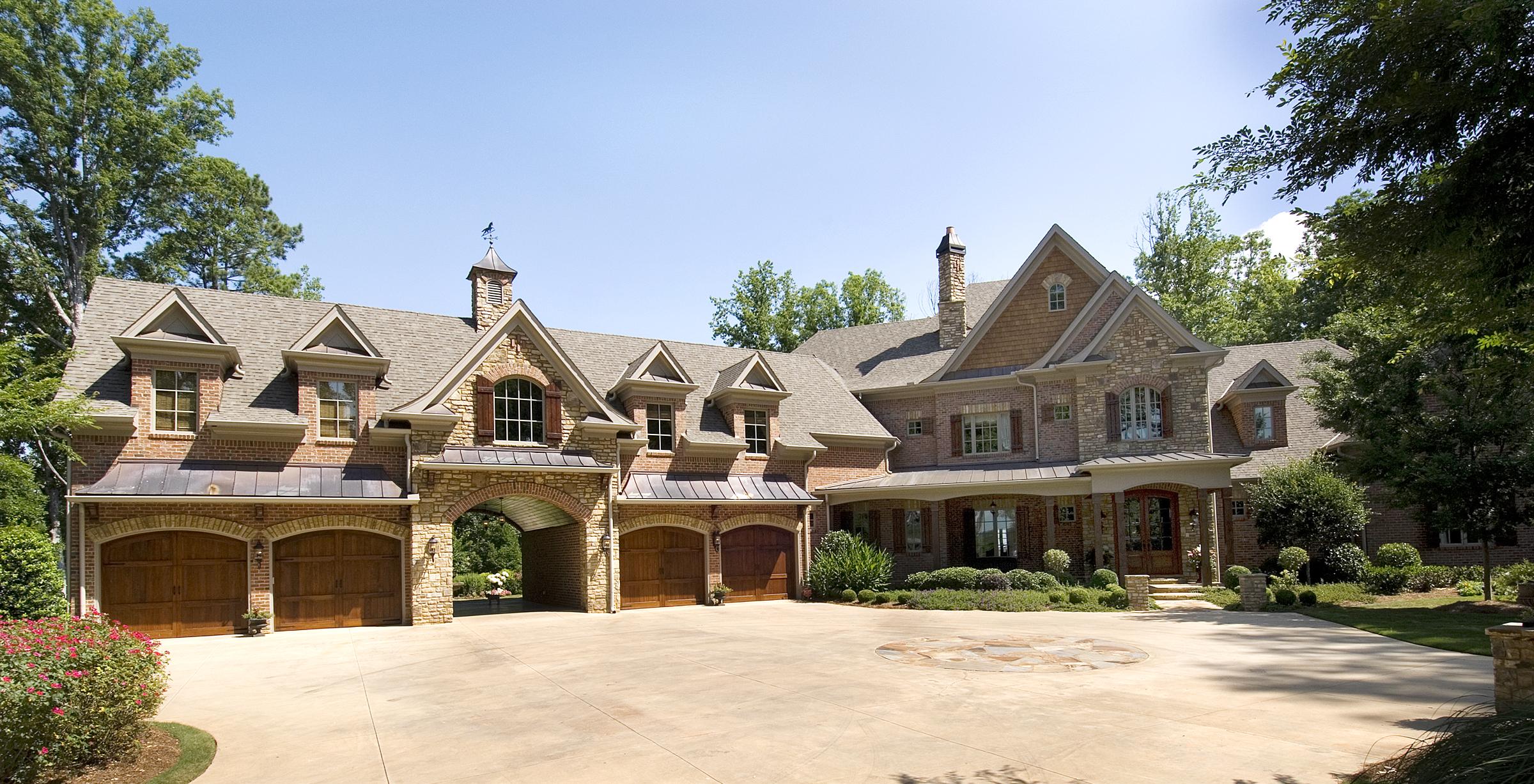 House plan exterior of a two-story brick and stone home with multiple gables, arched garages, and a covered entryway.