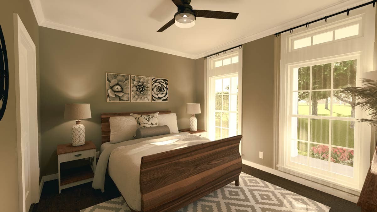 A bedroom with a wooden bed frame, bedside lamps, and a ceiling fan. Large windows offer a view of the outdoors, while wall art hangs above the bed.