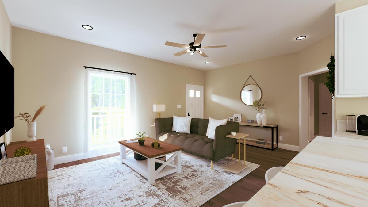 Living room with dark green sofa, white coffee table, ceiling fan, and natural light from large window.