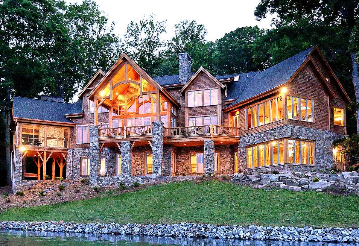 Mountain lodge style house plan exterior with stone and wood siding, multiple gables, and extensive glass.