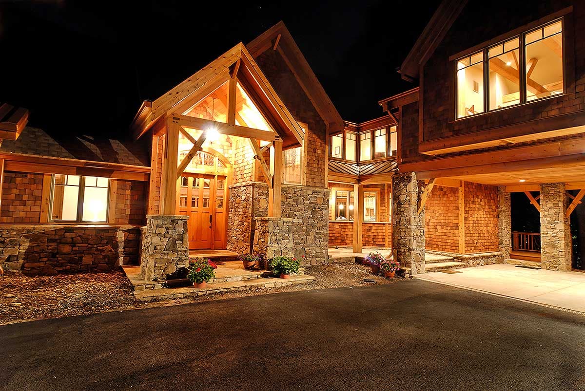 House plan exterior with stone accents, wood shake siding, prominent gable over entryway, and covered drive-through.