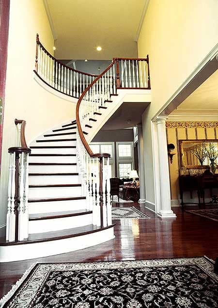 Curved open-riser staircase with white balusters and dark wood handrail, leading to upper level.