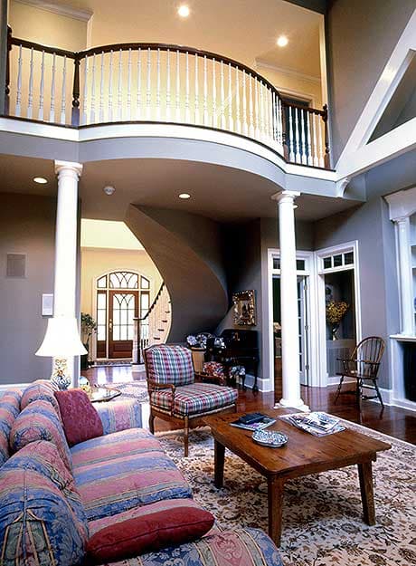 Interior view showing a grand entryway with a curved balcony, spiral staircase, and large windows.