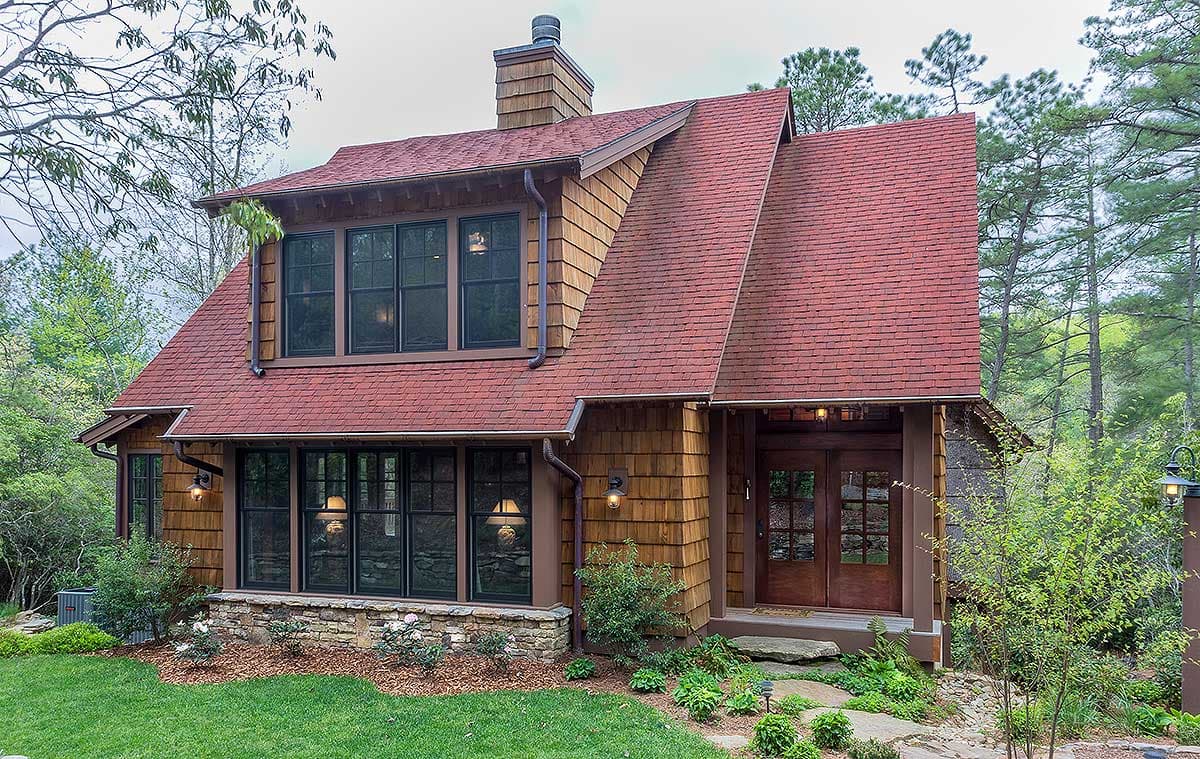 House plan exterior featuring wood shake siding, multi-level red roof, stone foundation, and double entry doors.