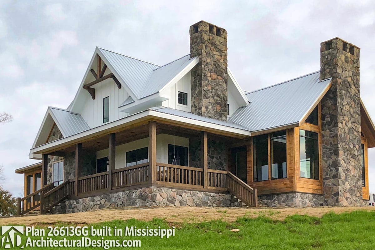 House plan exterior features metal roof, stone and board-and-batten siding, wide covered porch with wood posts, and large stone chimney.