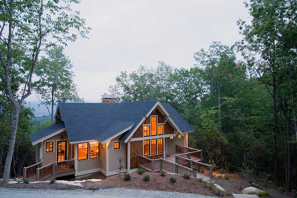 House plan exterior: wood shingle gable, multiple dormers, large windows, and wraparound decks.