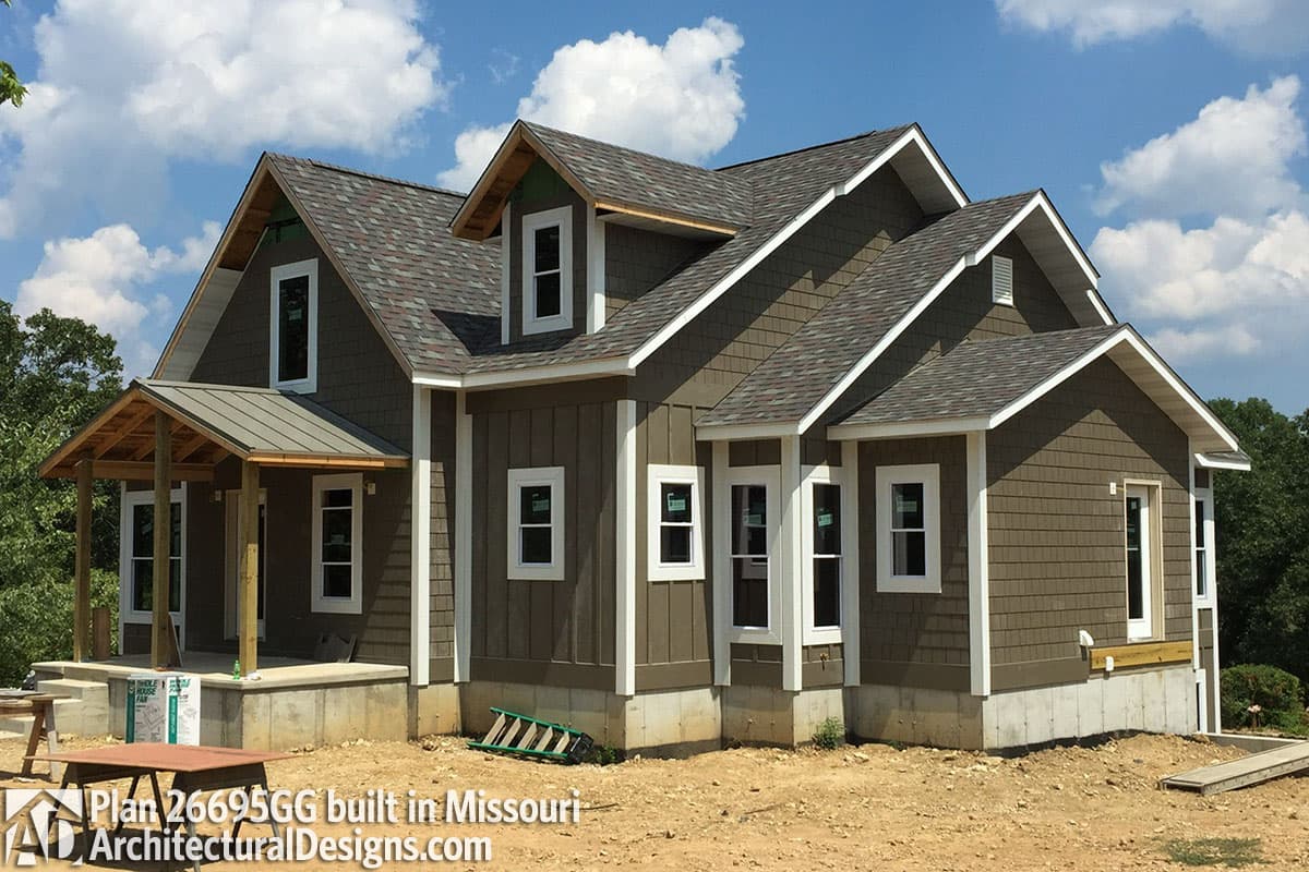 House plan exterior: two-story home with gables, dormers, and a covered front porch with metal roof.